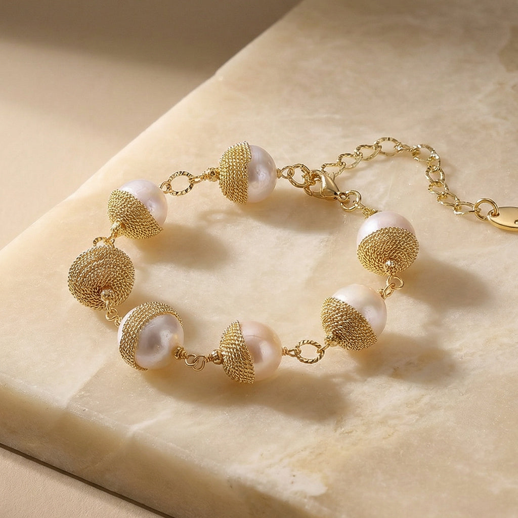 Baroque pearls are cocooned in sculptural gold mesh