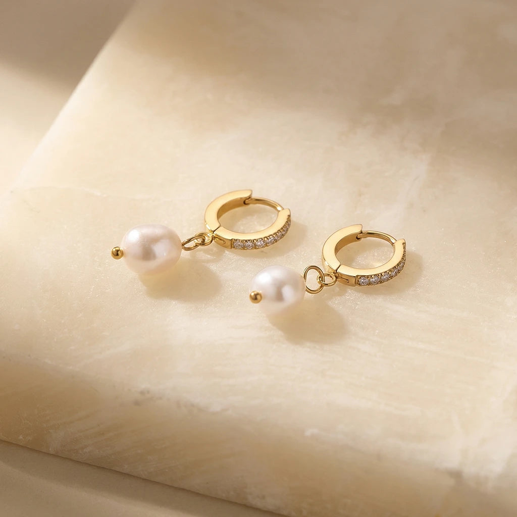 Golden Pearl Huggie Hoops on a stone