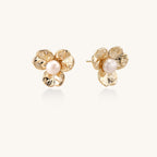 Gold-plated flower stud earrings with freshwater pearl centers on beige background, showing textured petal details.