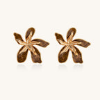 Large gold-plated flower earrings with brown enamel marbled petals on beige background, showing intricate floral design.