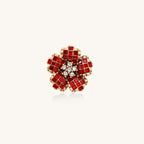 Statement ring with layered red crystal petals in gold-plated setting resembling a blooming flower on neutral background.