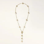 Gold-plated lariat necklace with baroque pearls and textured caps on cream background, showing adjustable Y-shaped design.