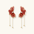 Floral earrings with red petals and gold accents on a white background