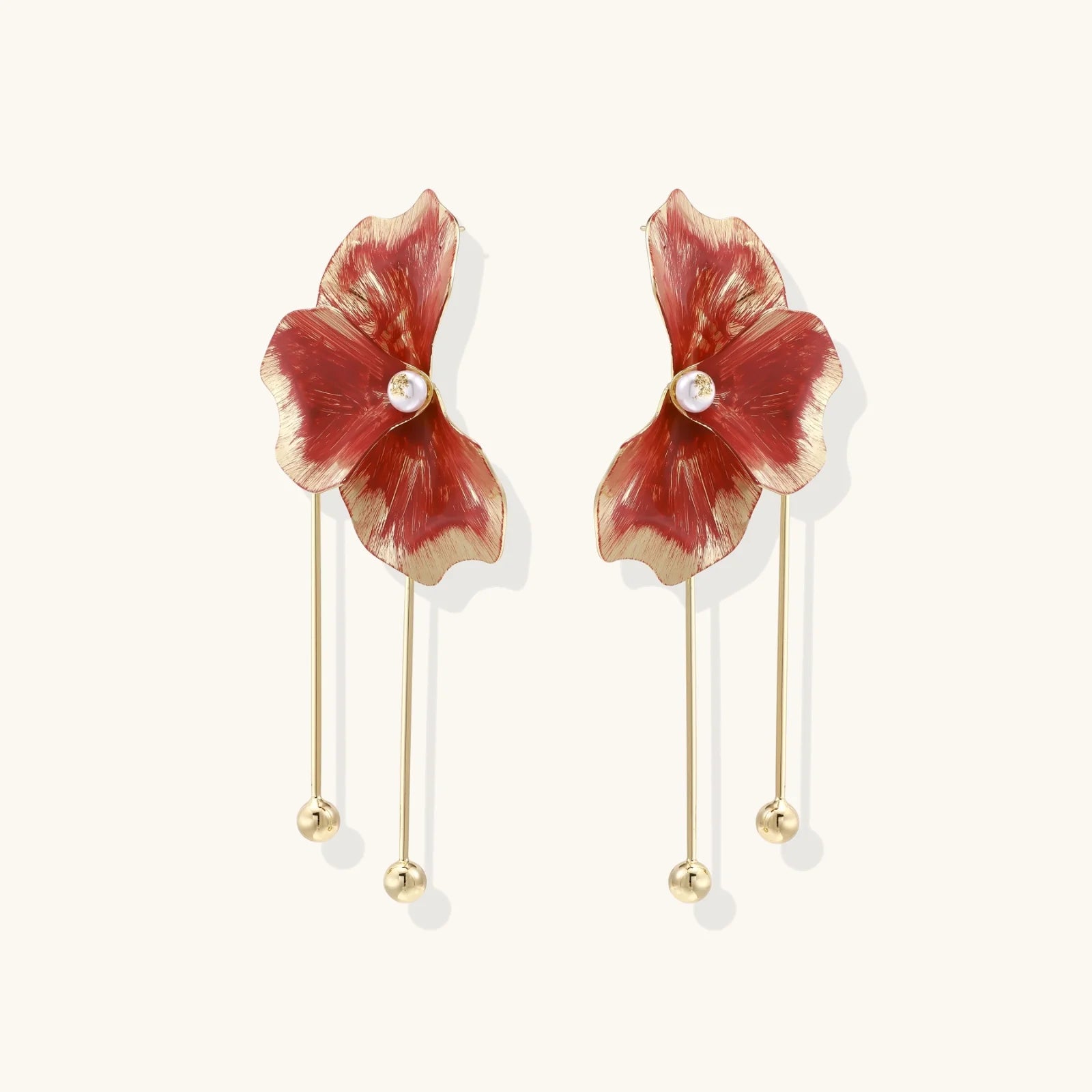 Floral earrings with red petals and gold accents on a white background