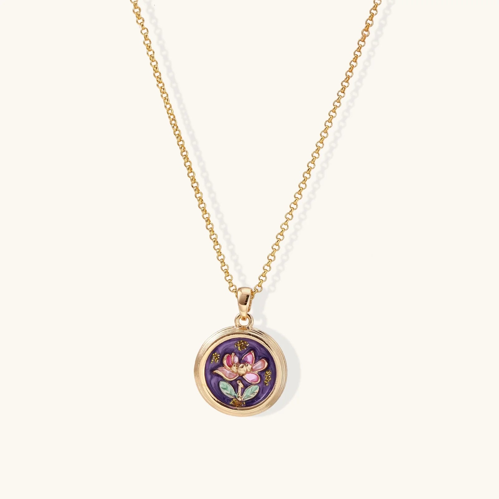 Gold necklace with a round pendant featuring a floral design on a white background