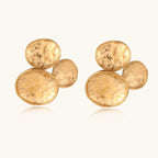Three hammered gold discs clustered together forming organic statement earrings with textured surfaces