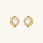 Circular gold stud earrings with iridescent mother-of-pearl center and green zirconia accents on cream background.