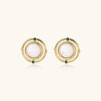 Circular gold stud earrings with iridescent mother-of-pearl center and green zirconia accents on cream background.