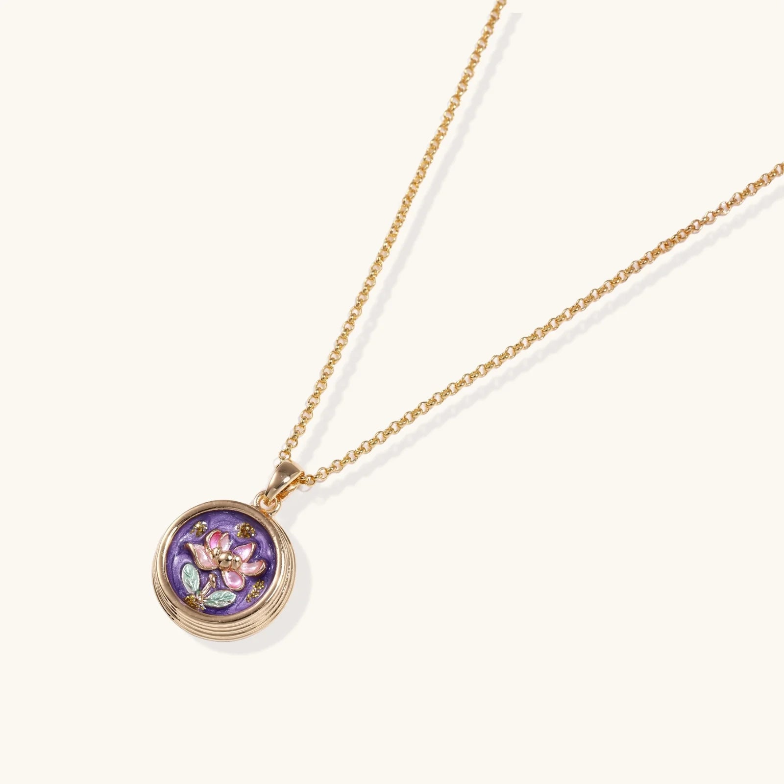 Gold necklace with a purple pendant featuring a floral design on a white background