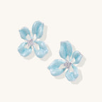 Pair of light blue flower-shaped earrings on a white background