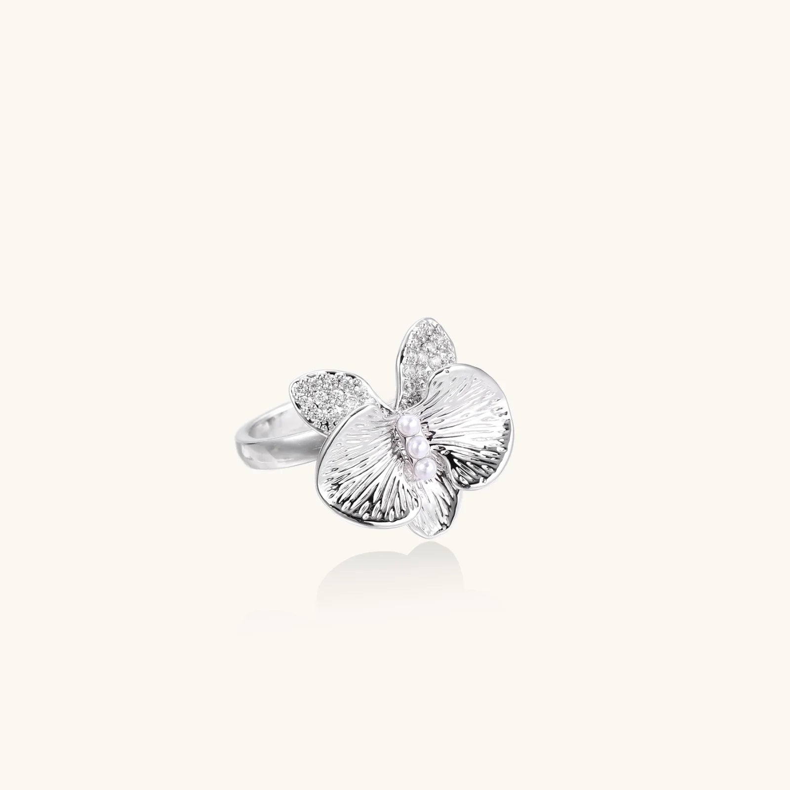 Silver-toned orchid ring with textured petals, pearl center accents, and sparkling zirconia stones on white background.