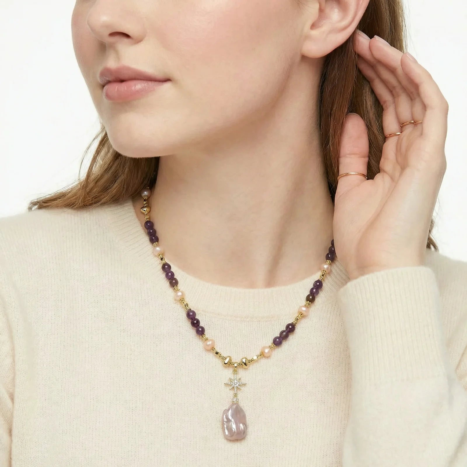 Woman wearing a beaded necklace with a pendant, adjusting it with her hand.