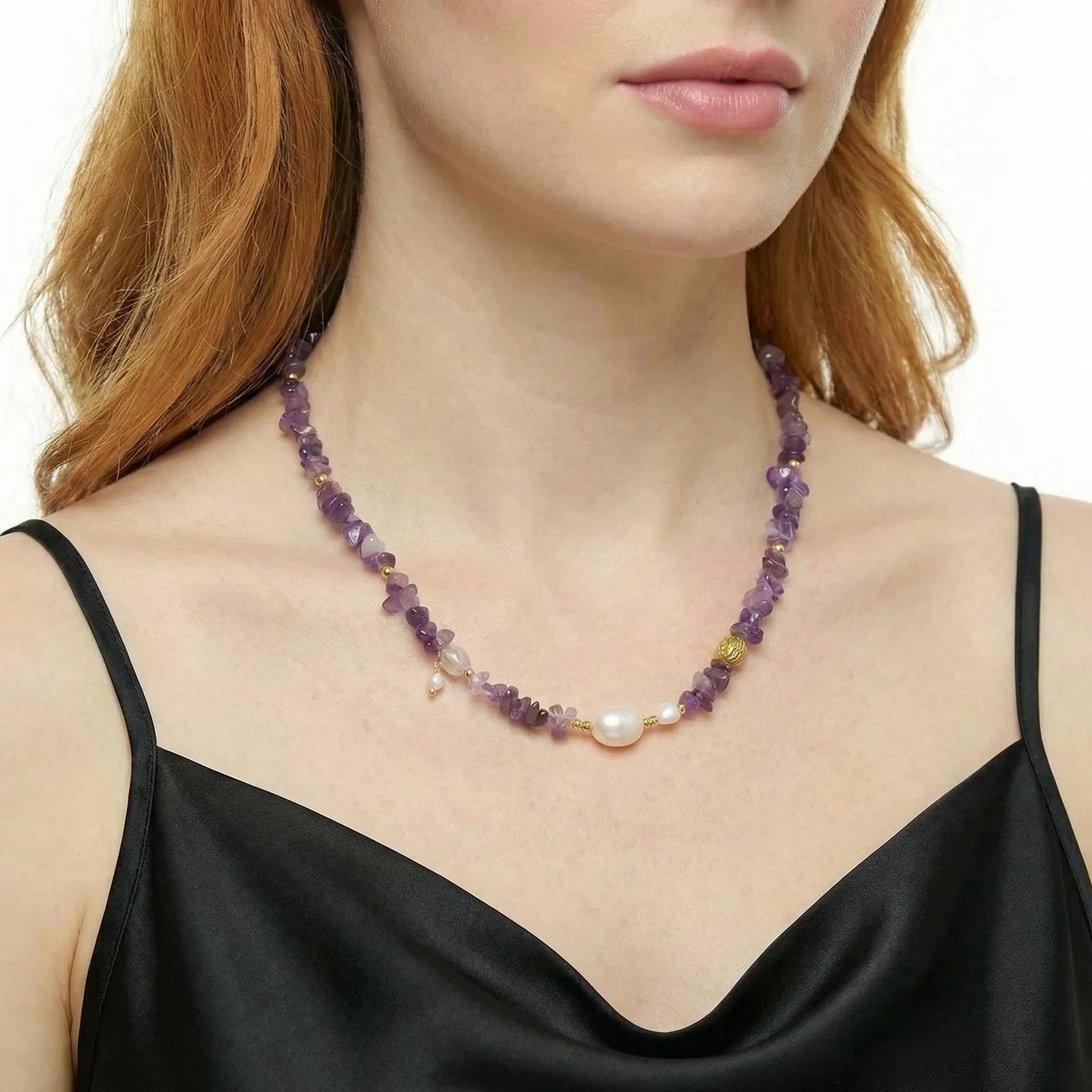 Person wearing a beaded necklace with purple amethyst beads and a pearl, against a white background.