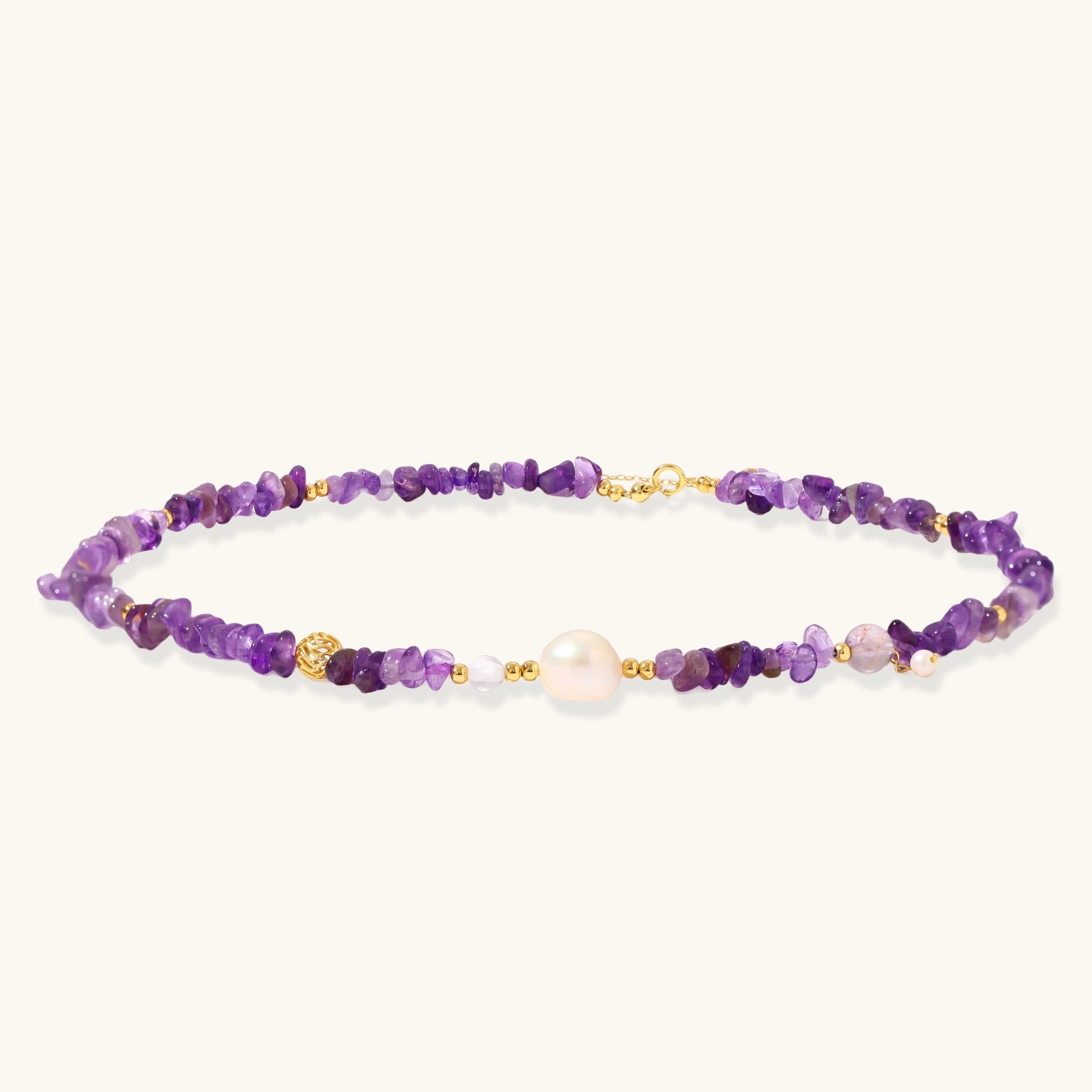 Beaded necklace with purple amethyst chips, freshwater pearls, and gold accents on white background.
