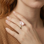 Hand wearing a pink pearl ring and gold celestial star 