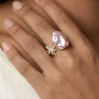 Hand wearing a pink pearl ring and gold star