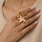 Hand wearing a gold butterfly ring on a neutral background