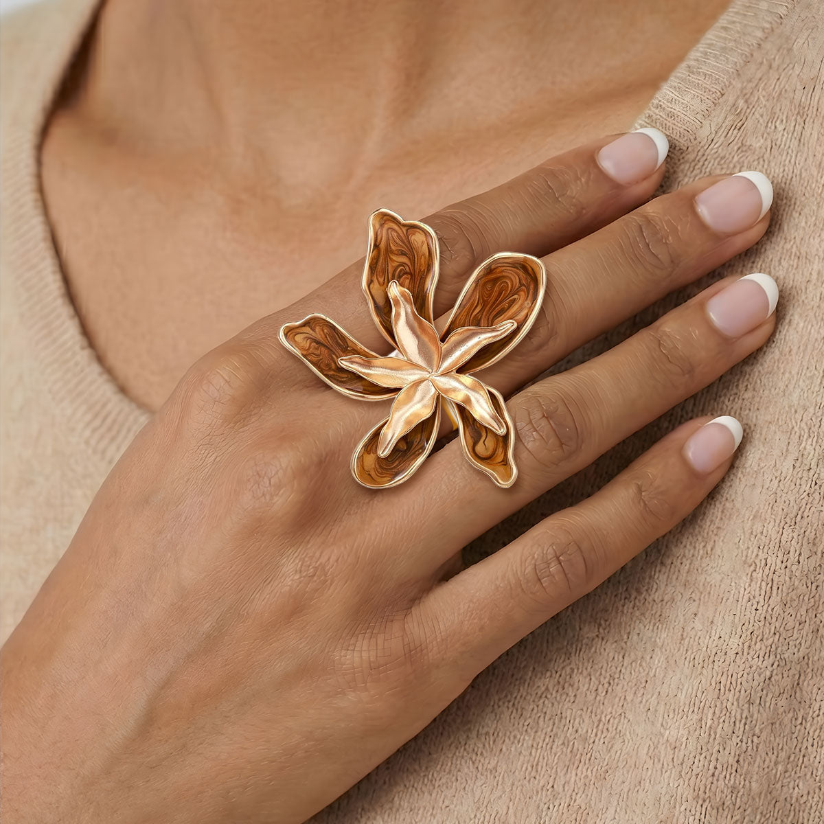 Hand wearing a gold butterfly ring on a neutral background