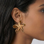 Close-up of a person wearing a gold butterfly earring.