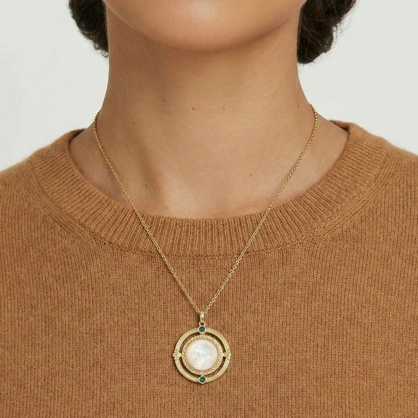 Necklace with a pendant worn by a person against a neutral background