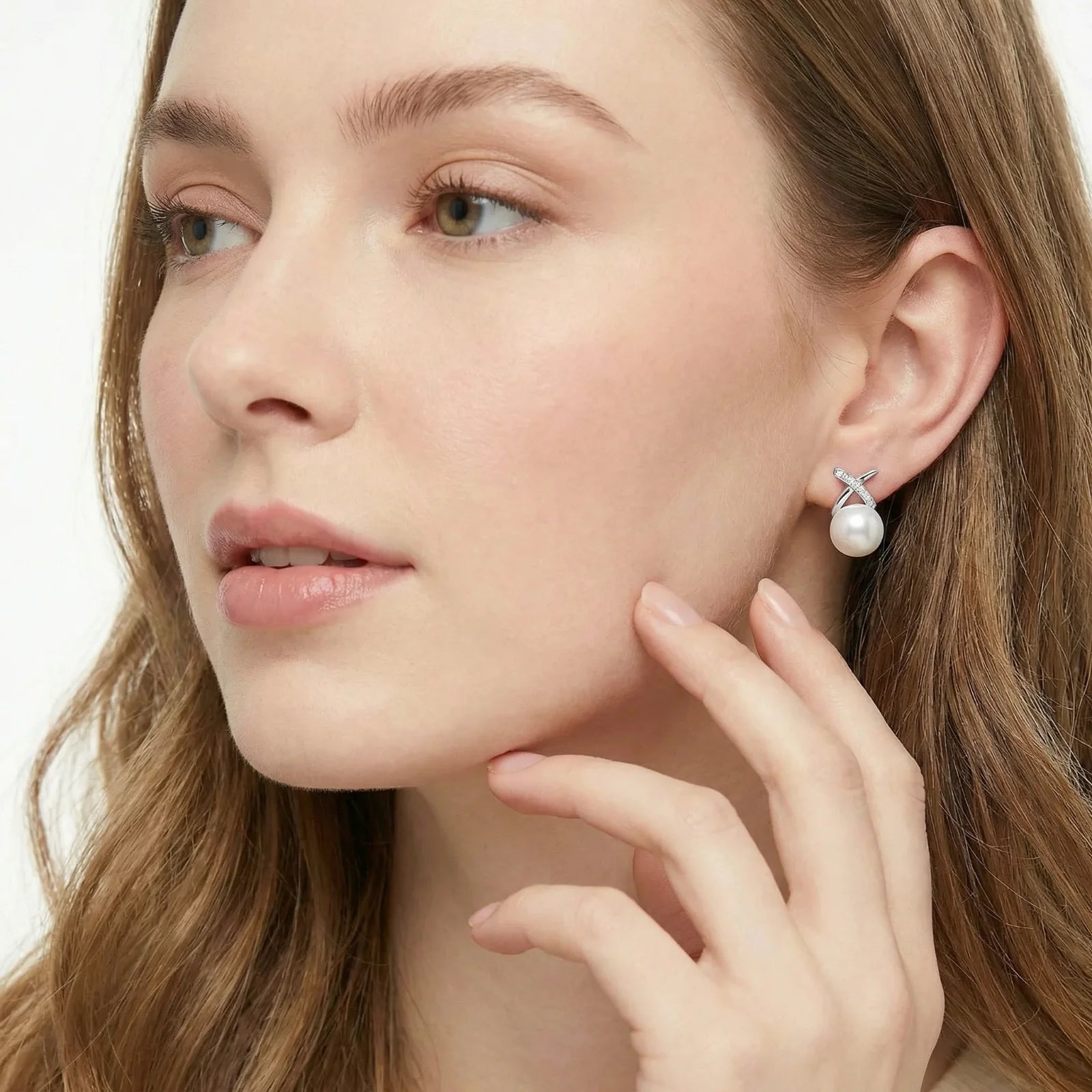 Close-up of a woman wearing pearl earrings on a plain background