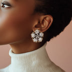 Close-up of a woman wearing a decorative earring with a soft pink background
