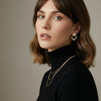 Woman wearing geometric gold jewelry against a neutral background