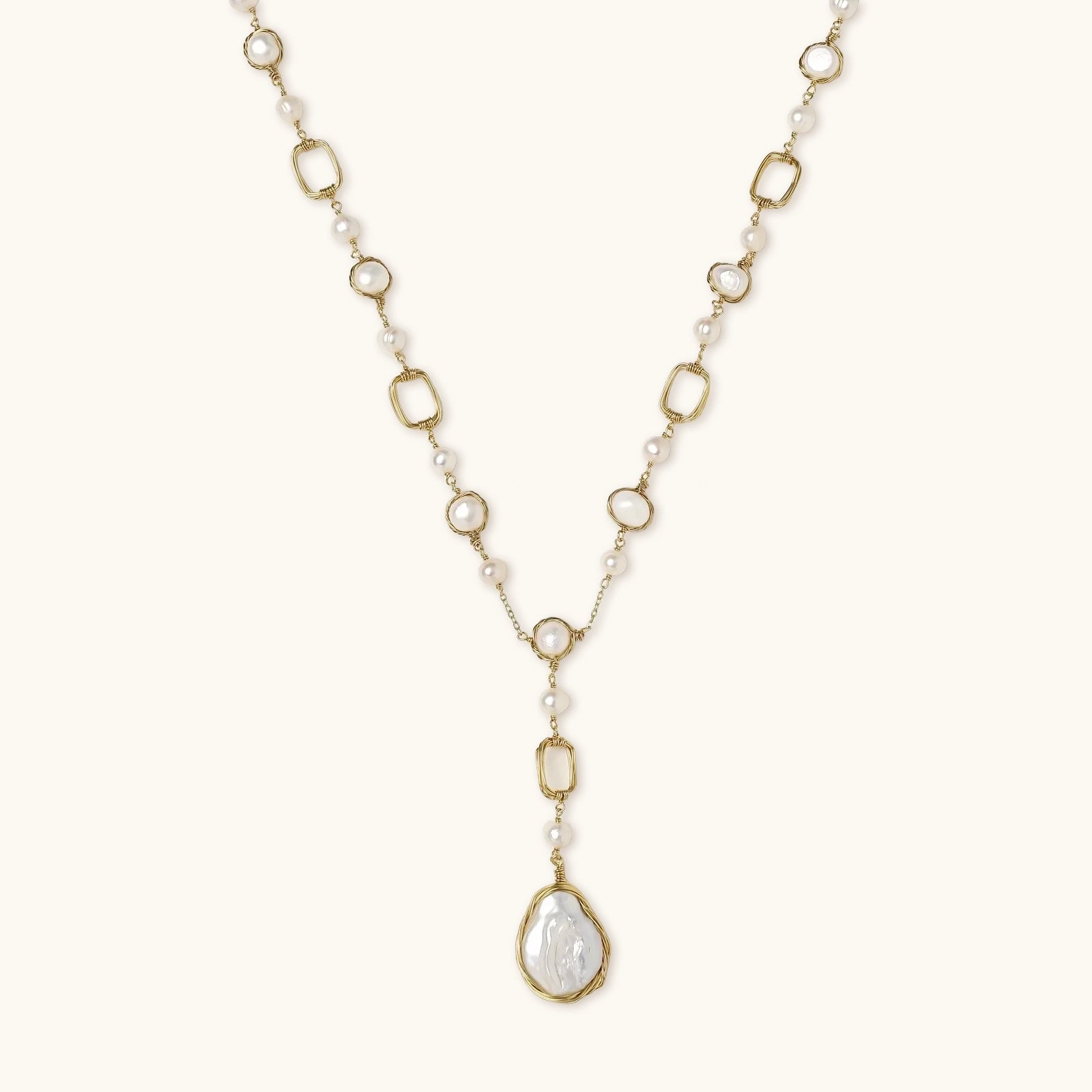 Gold and pearl necklace on a light beige background
