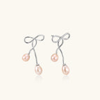 Pair of silver earrings shaped like a ribbon with pink pearls on a white background