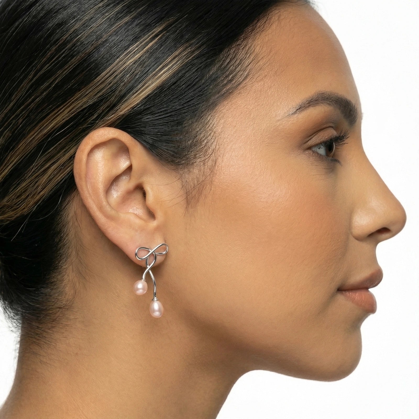 Close-up of a woman wearing a silver earring with pearls on a white background