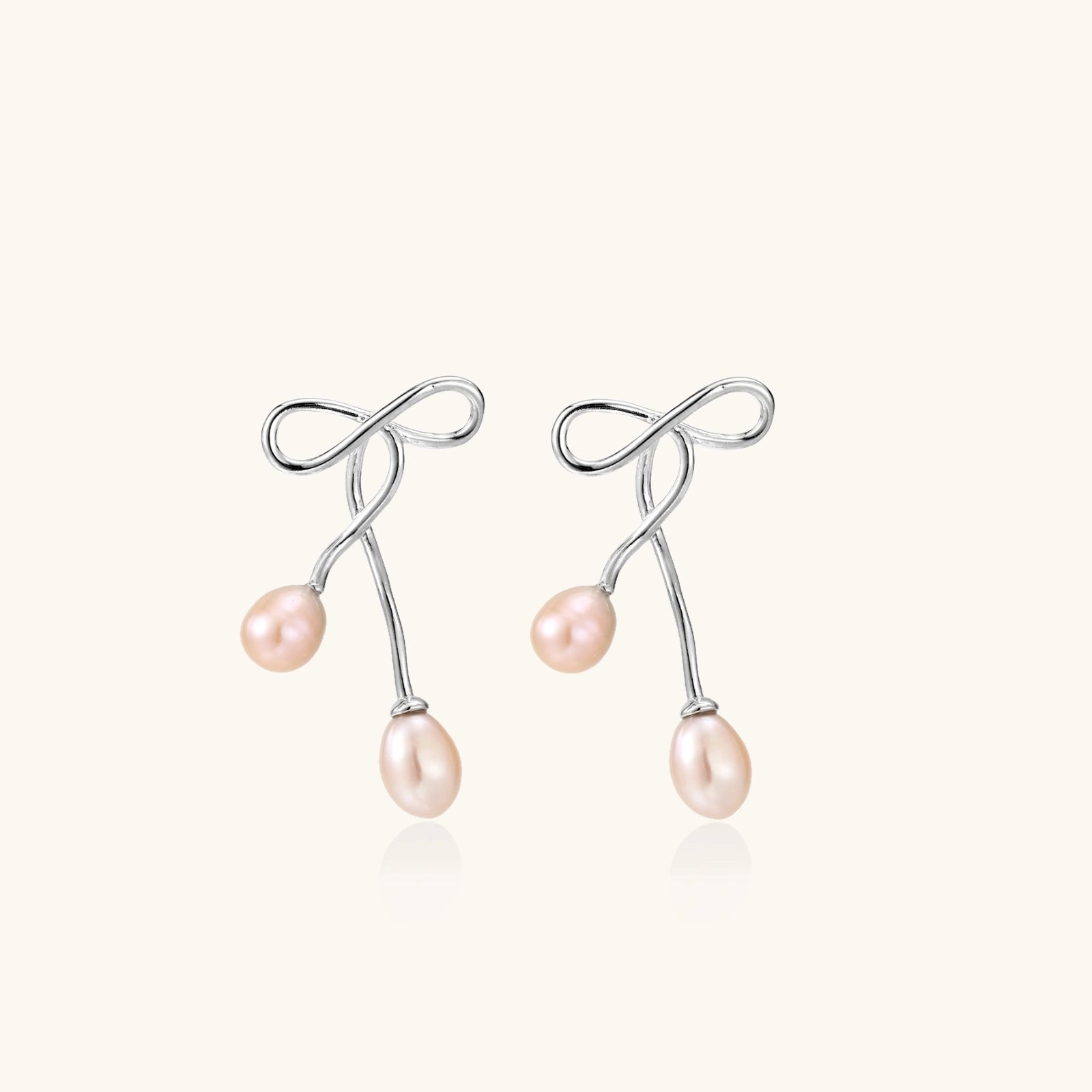 Pair of silver earrings with pink pearls on a white background