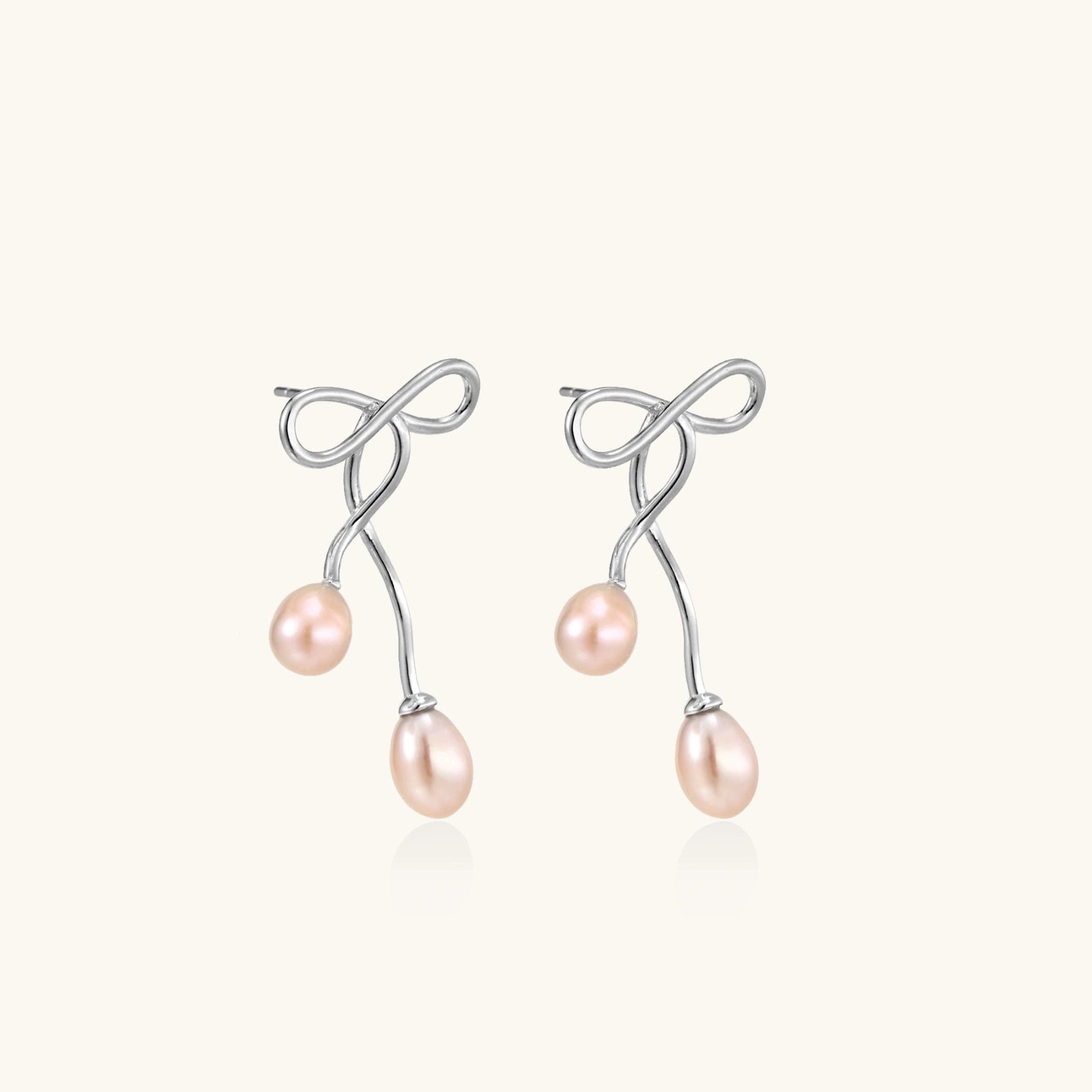 Pair of silver earrings with pink pearls on a white background