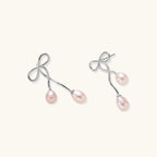 Pair of silver earrings with pink pearls on a white background