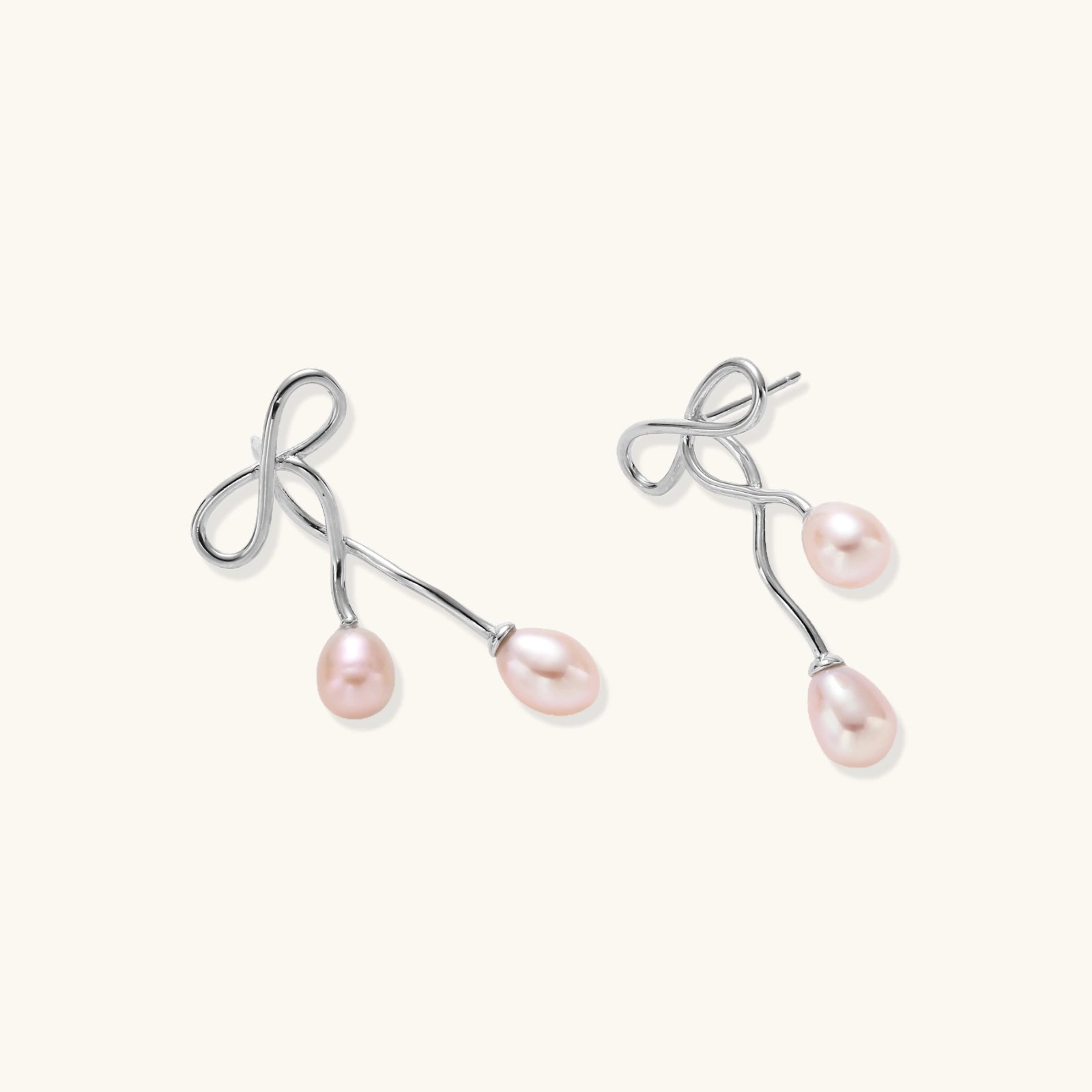 Pair of silver earrings with pink pearls on a white background