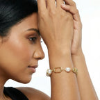 Woman wearing a gold bracelet with pearls on a white background