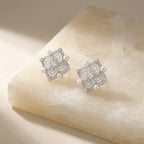 Silver earrings with pearl accents on a beige stone surface