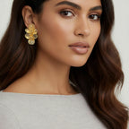 Woman wearing gold floral earrings with a neutral background