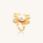 Gold ring with dimensional 4-petal flower design and white cotton pearl center on neutral background