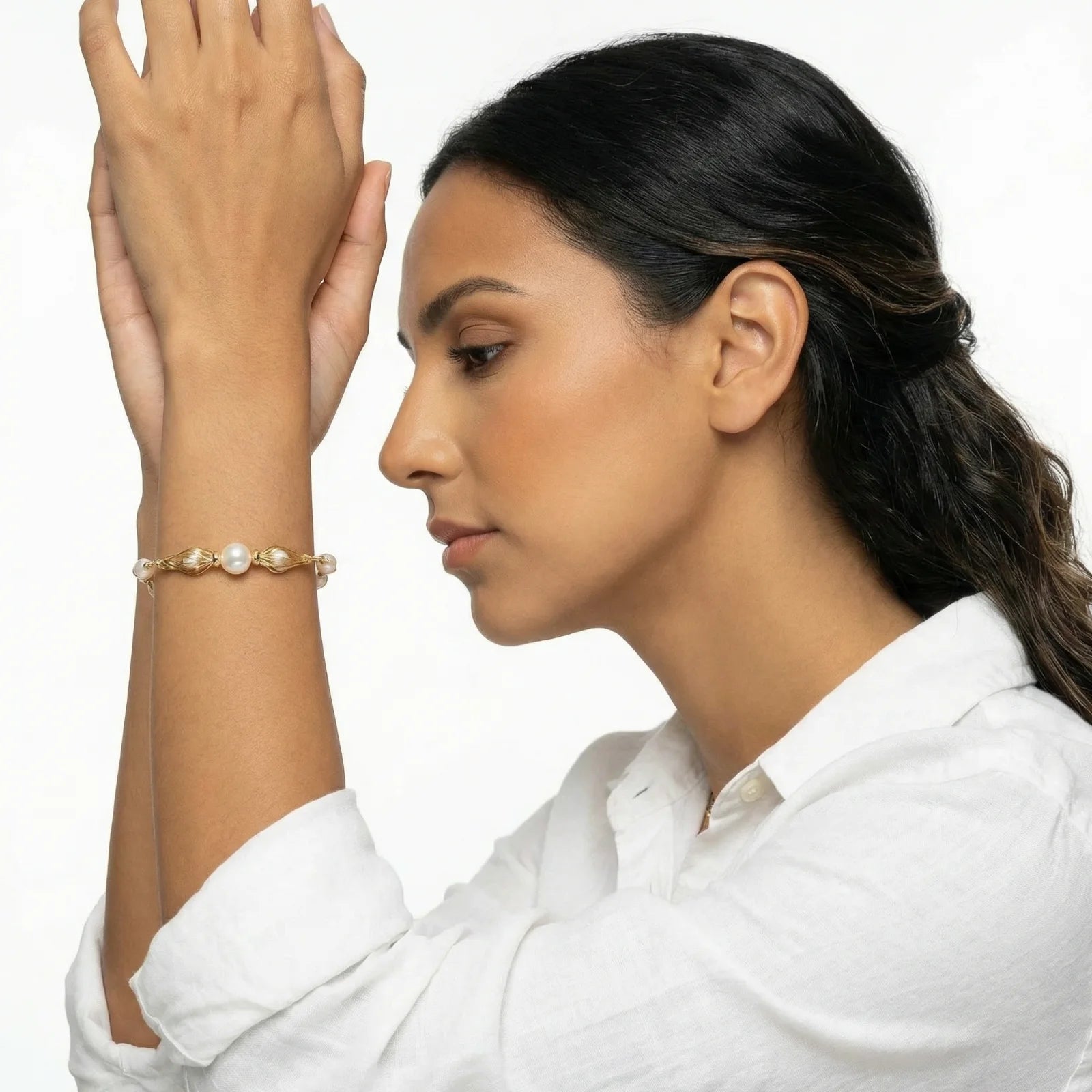 Woman wearing a gold bracelet with pearls on a white background