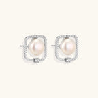 Rhodium-plated silver stud earrings with cushion frame, centered freshwater pearl, and tiny crystal accent