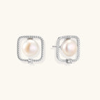 Rhodium-plated silver stud earrings with cushion frame, centered freshwater pearl, and tiny crystal accent