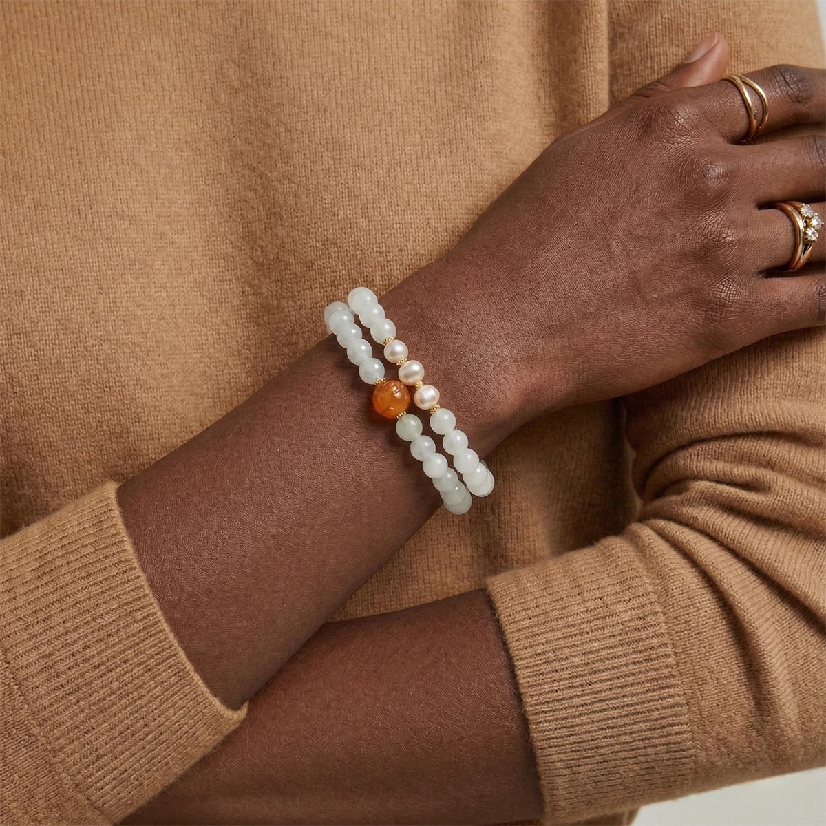 Close-up of a hand wearing a bracelet with beads on a beige background