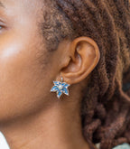 Pair of maple-leaf-shaped earrings with denim fabric and pearls on a white background