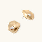Gold earrings with a white center on a light beige background
