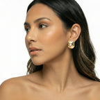 Close-up of a woman wearing gold earrings on a white background