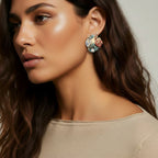 Close-up of a woman wearing a colorful monstera-shaped earrings with a neutral background