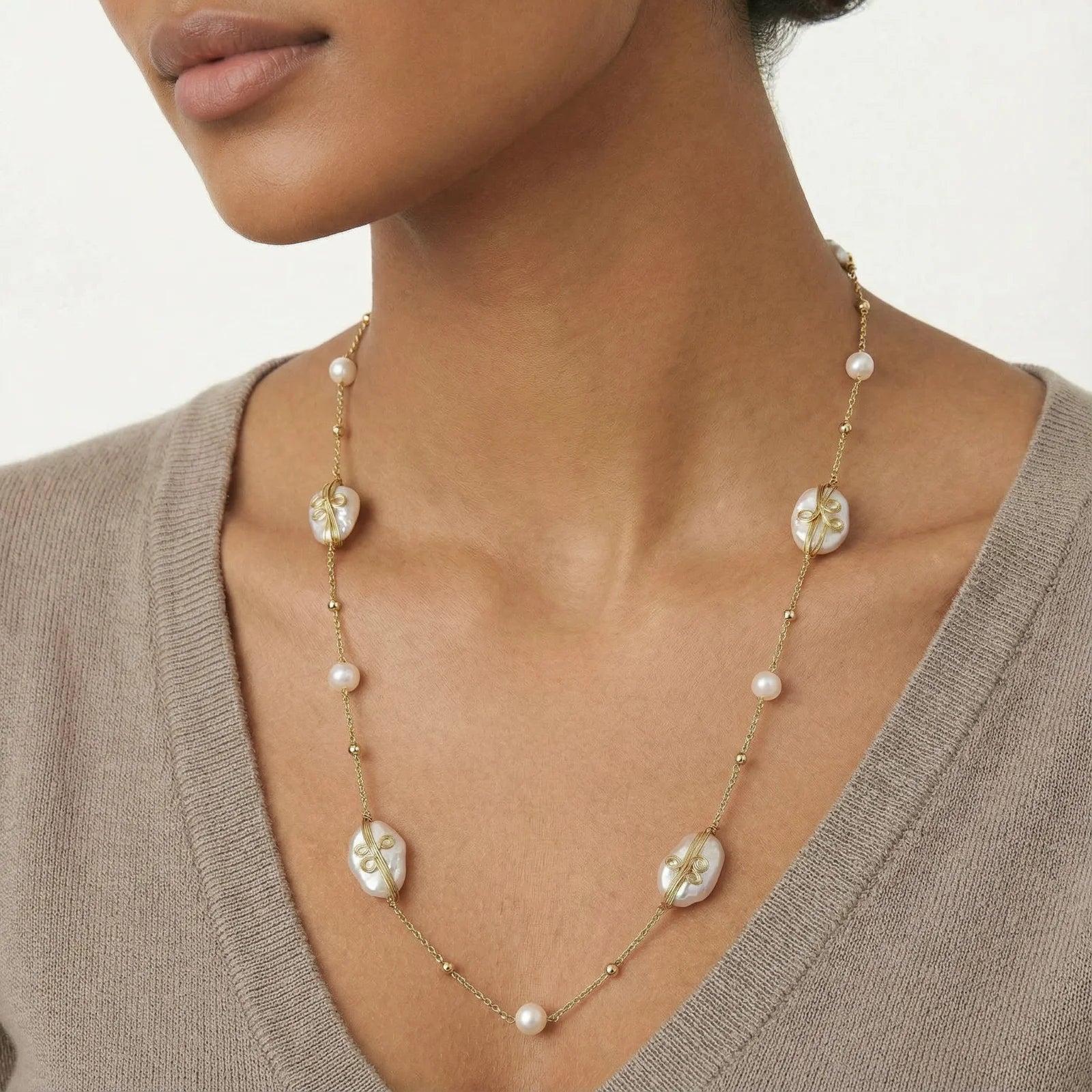 Necklace with floral and pearl designs worn by a person against a neutral background