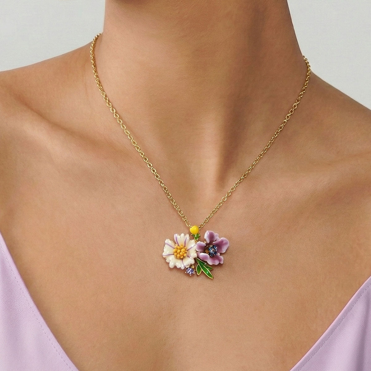 Necklace with a floral pendant on a person wearing a light purple top.