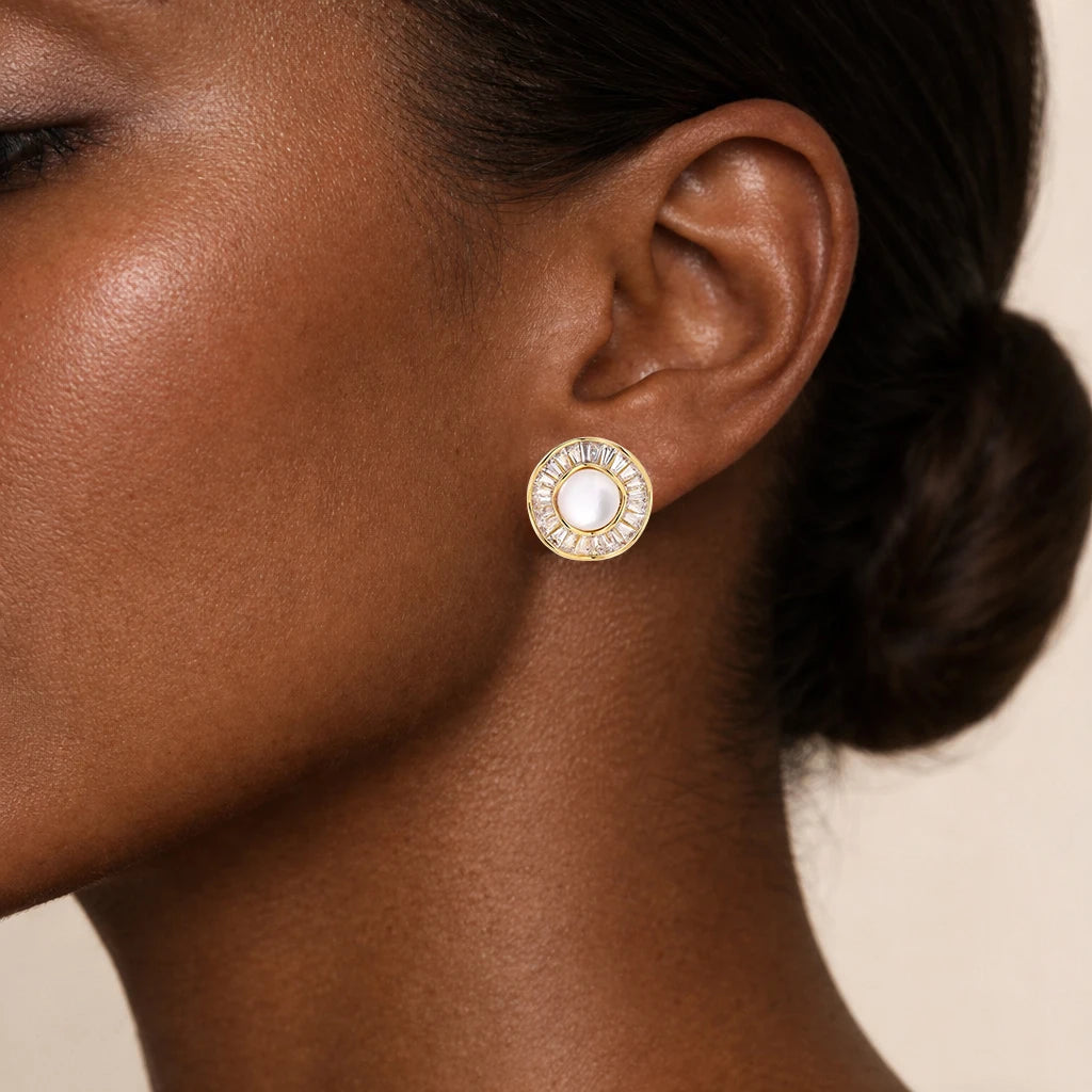Close-up of a woman's ear wearing gold earrings with a pearl center.