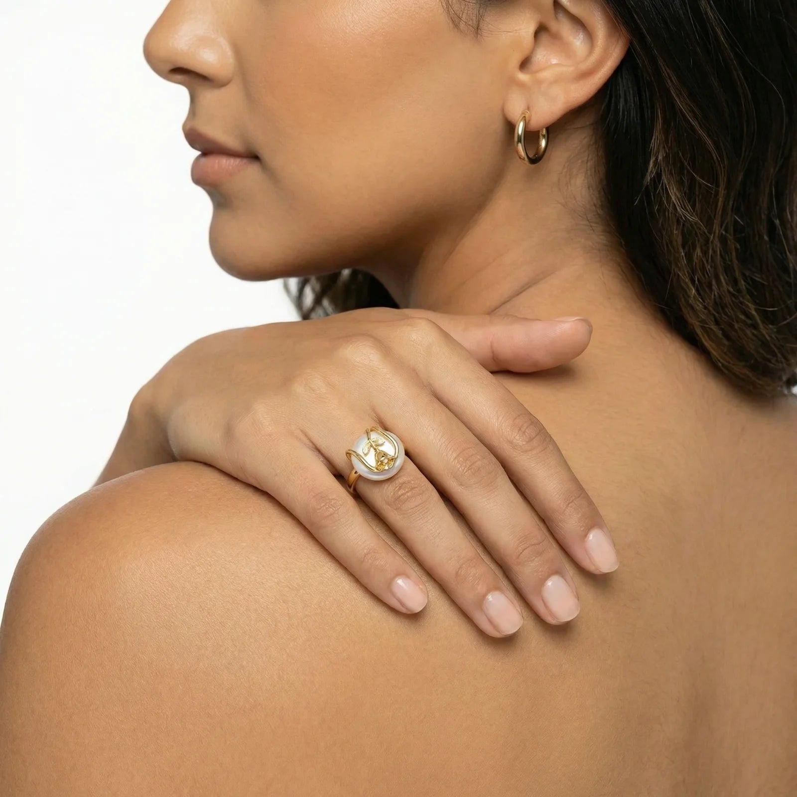 Woman wearing a gold ring with a diamond on a neutral background